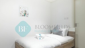 A bedroom with a wooden bed, white bedding, and a wall art piece. - Bloomfields Metropolitan 3BR In Bridges (Abu Dhabi)