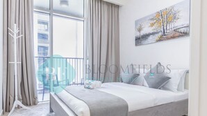 A modern bedroom with a large bed, a balcony, and a painting on the wall. - Bloomfields Metropolitan 3BR In Bridges (Abu Dhabi)