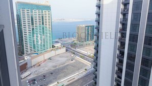 A high-rise hotel with multiple floors, a view of the sea, and a parking area in the foreground. - Bloomfields Metropolitan 3BR In Bridges (Abu Dhabi)