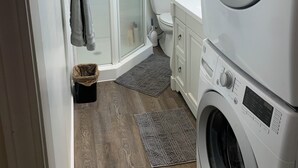 A compact laundry room with a front-loading washer and dryer, a shower enclosure, and a toilet. -  JC'S Place #3 (Hebron)