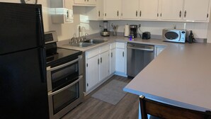 A modern kitchen with white cabinets, stainless steel appliances, and a wooden ceiling. -  JC'S Place #3 (Hebron)
