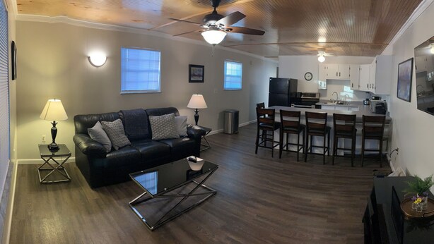 A living room with a black leather sofa, a glass coffee table, and a dining area with wooden chairs and a white table. -  JC'S Place #3 (Hebron)