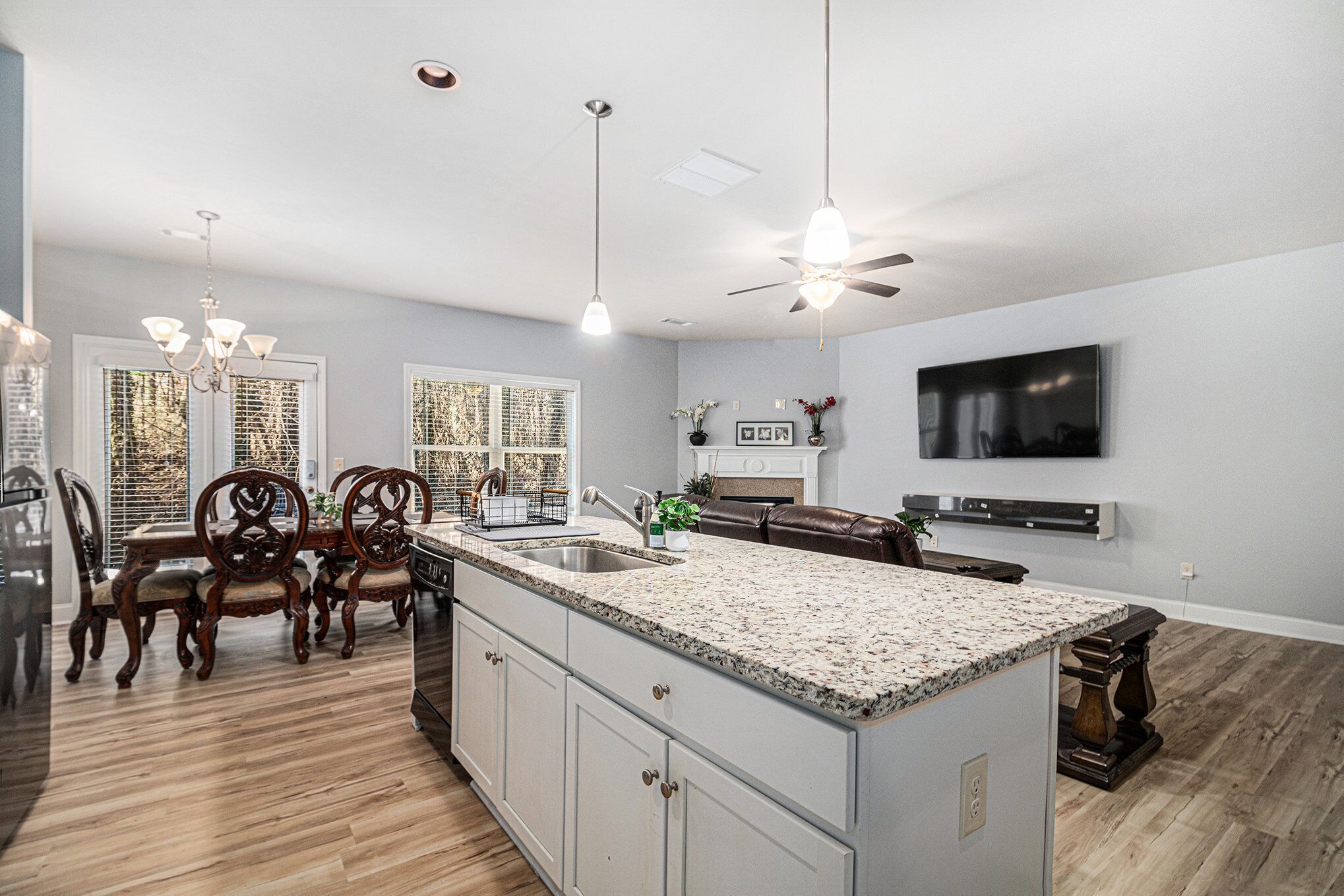 A modern kitchen with a large island, wooden dining table, and chairs.