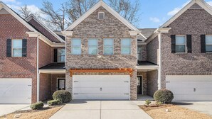 A two-story residential building with a brick facade, a central garage, and a small front porch.