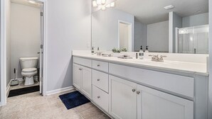 A modern bathroom with a white vanity, a large mirror, and a shower area.
