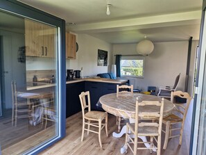 Une cuisine moderne avec des meubles en bois, une table à manger avec des chaises et une grande fenêtre offrant une vue dégagée.