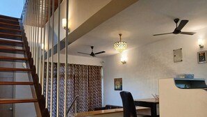 A modern interior with a staircase, a dining area, and ceiling fans. - Villa MTDC registeredwithSwimming pool,Lift,Microwave,Washingmachine,Wifiparking (Lonavala)