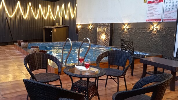 A pool area with wicker chairs and tables, a tiled pool, and decorative lighting. - Villa MTDC registeredwithSwimming pool,Lift,Microwave,Washingmachine,Wifiparking (Lonavala)