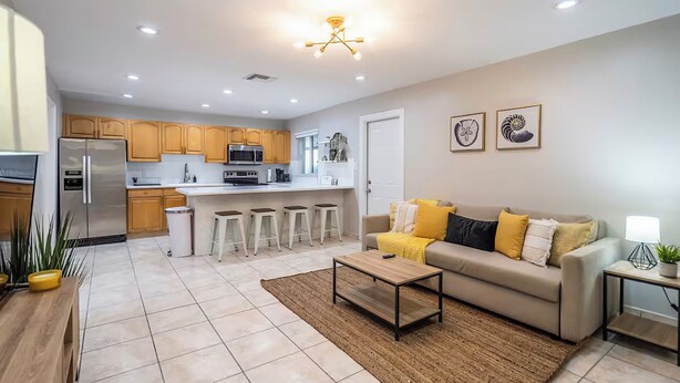 A modern kitchen with wooden cabinets, a stainless steel refrigerator, and a central island with stools.