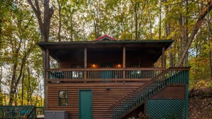 A two-story log cabin with a balcony, a staircase, and a green door. - Big Oak Cabin (Hocking Hills area) (Rockbridge)