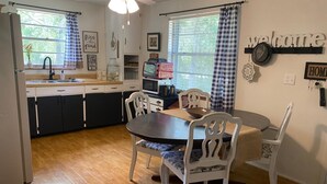 A kitchen with a dining table, chairs, a ceiling fan, and a 'welcome' sign.