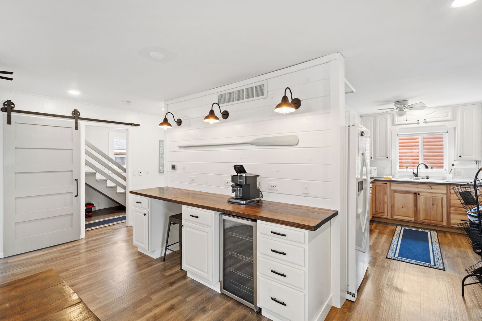 Una cocina moderna con armarios blancos, encimera de madera e iluminación colgante.