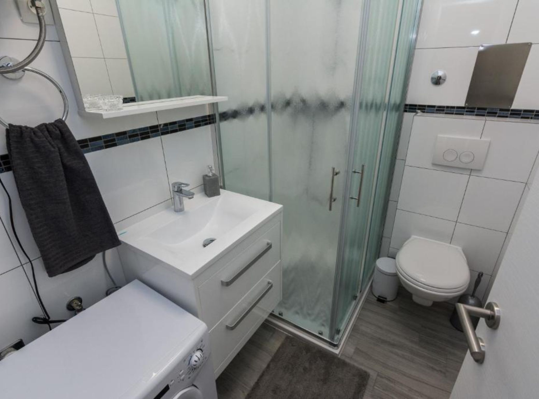 A modern bathroom with a glass shower enclosure, a white sink, and a toilet.