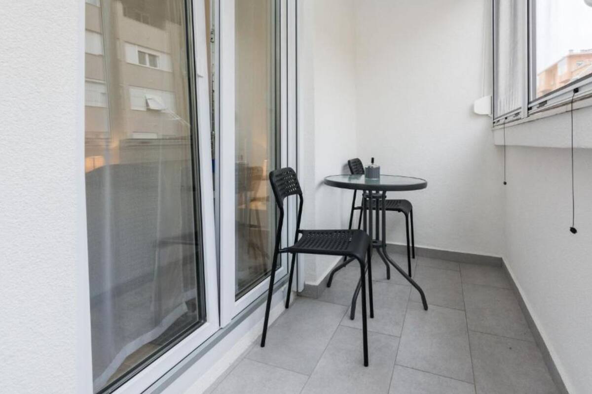 A small balcony with a glass door, a round table, and two chairs.