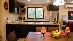 Una cocina moderna con una isla grande, electrodomésticos de acero inoxidable e iluminación colgante.
