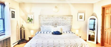 A bedroom with a large bed, a decorative headboard, bedside lamps, and a ceiling light fixture.