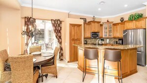 A modern kitchen with wooden cabinets, a stainless steel refrigerator, and a granite countertop. - Spacious and Private Pool Home- Pet Friendly (Naples)