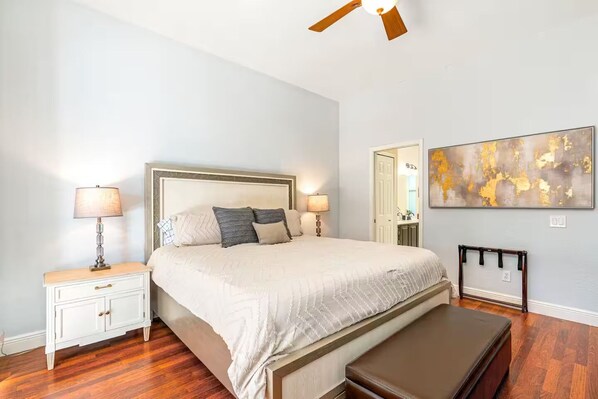 A bedroom with a large bed, bedside tables, a bench, a ceiling fan, and a wall-mounted TV. - Spacious and Private Pool Home- Pet Friendly (Naples)