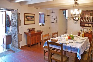 A dining area with a stone wall, a wooden table set for four, and a chandelier. - Casa del Moral (Vega de San Mateo)