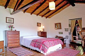 A bedroom with a wooden ceiling, a bed with a patterned bedspread, a dresser, and a nightstand. - Casa del Moral (Vega de San Mateo)