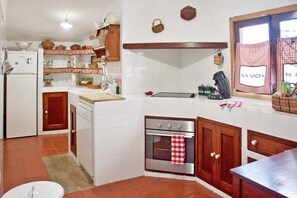 Una cuina amb armaris blancs, fogó, forn i nevera.