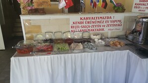 A buffet table with various food items and a sign in Turkish. - benjy motel pansiyon (Akcay)