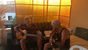 Two people sitting on a couch playing guitars. - benjy motel pansiyon (Akcay)