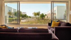 A living room with a large window, a sofa, and a coffee table. - Perfectly located apartment. Close to the town and the beaches. (Fuseta)