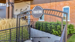 Une enseigne métallique portant les inscriptions « Windsor Mill Tavern » et « Fondé en 2019 », le tout disposé sur une structure incurvée.