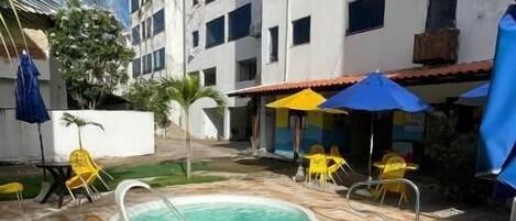A pool area with two hot tubs, surrounded by lounge chairs and umbrellas.