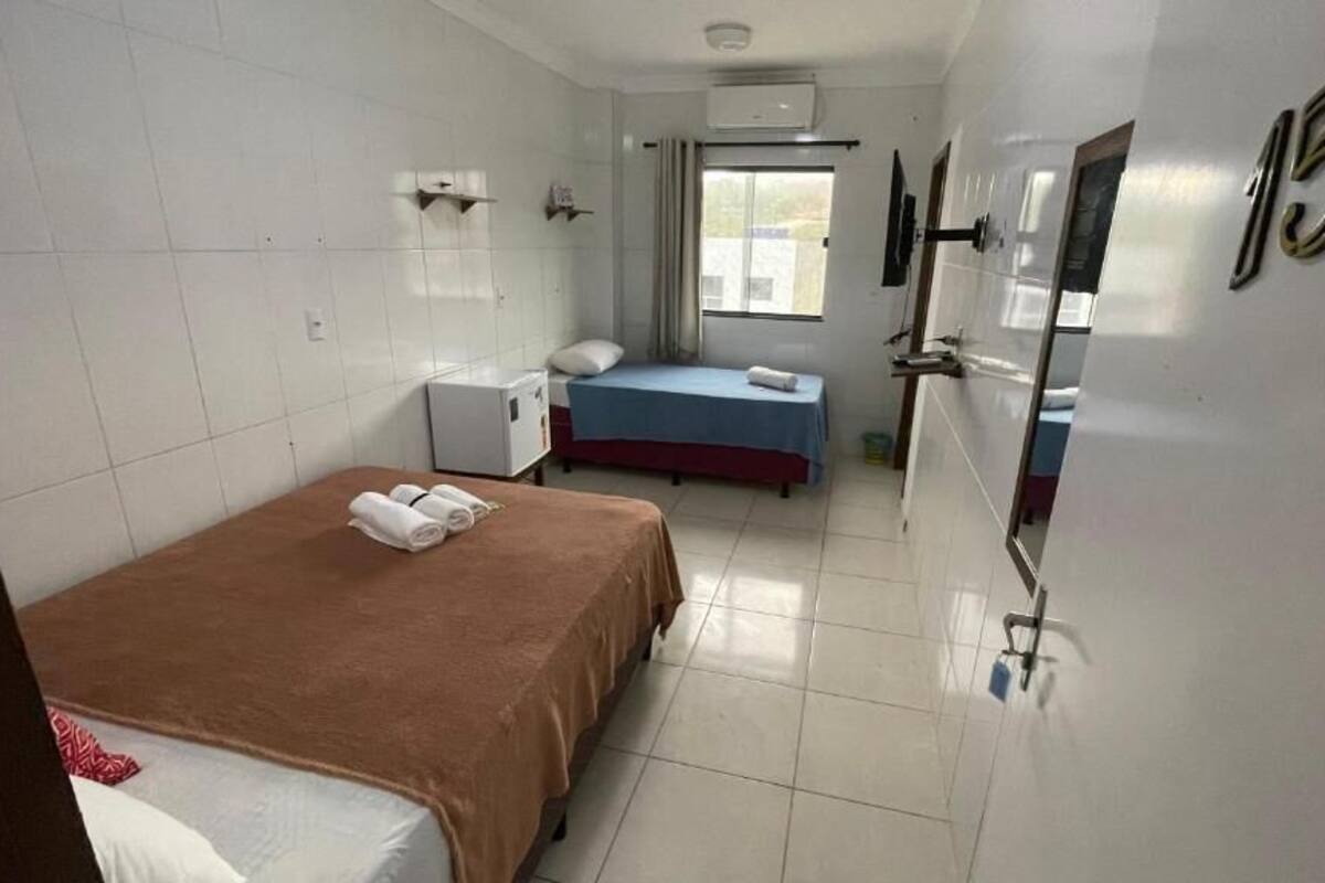 Ein Hotelzimmer mit zwei Betten, einem kleinen Schreibtisch, einem Fenster und einer Tür mit der Nummer 15.