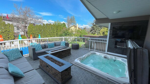 Une terrasse extérieure dotée d’un jacuzzi, d’un espace salon et offrant une vue sur une piscine et des arbres.