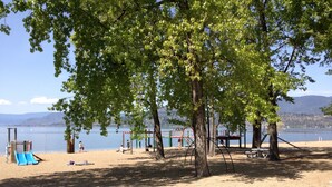 Une plage dotée d’une aire de jeux, comprenant des toboggans et des balançoires, ainsi qu’un sentier menant à la plage.