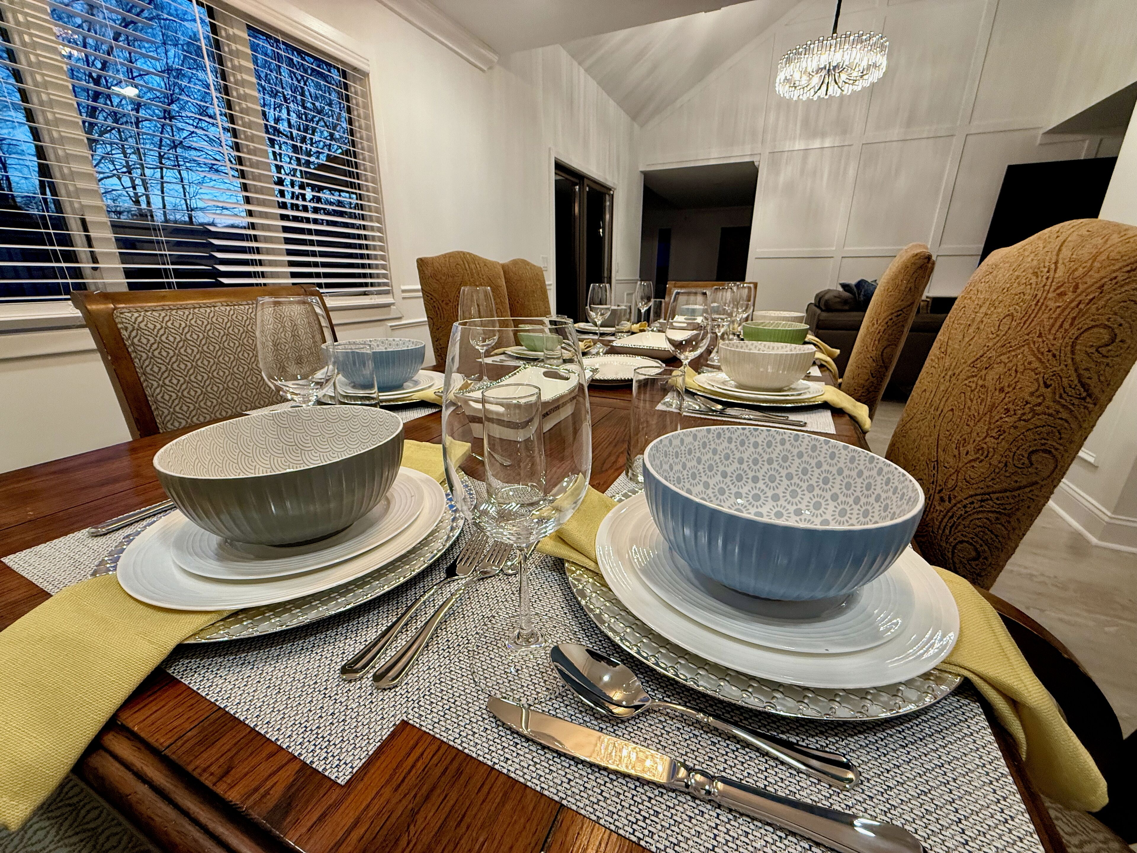 Une salle à manger avec une table en bois dressée pour le repas, entourée de chaises à motifs.