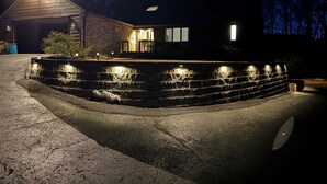 Una casa con un muro de contención de piedra y un camino de entrada.