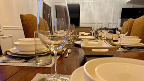 Una mesa de comedor preparada para una comida, con varios platos, vasos y cubiertos.