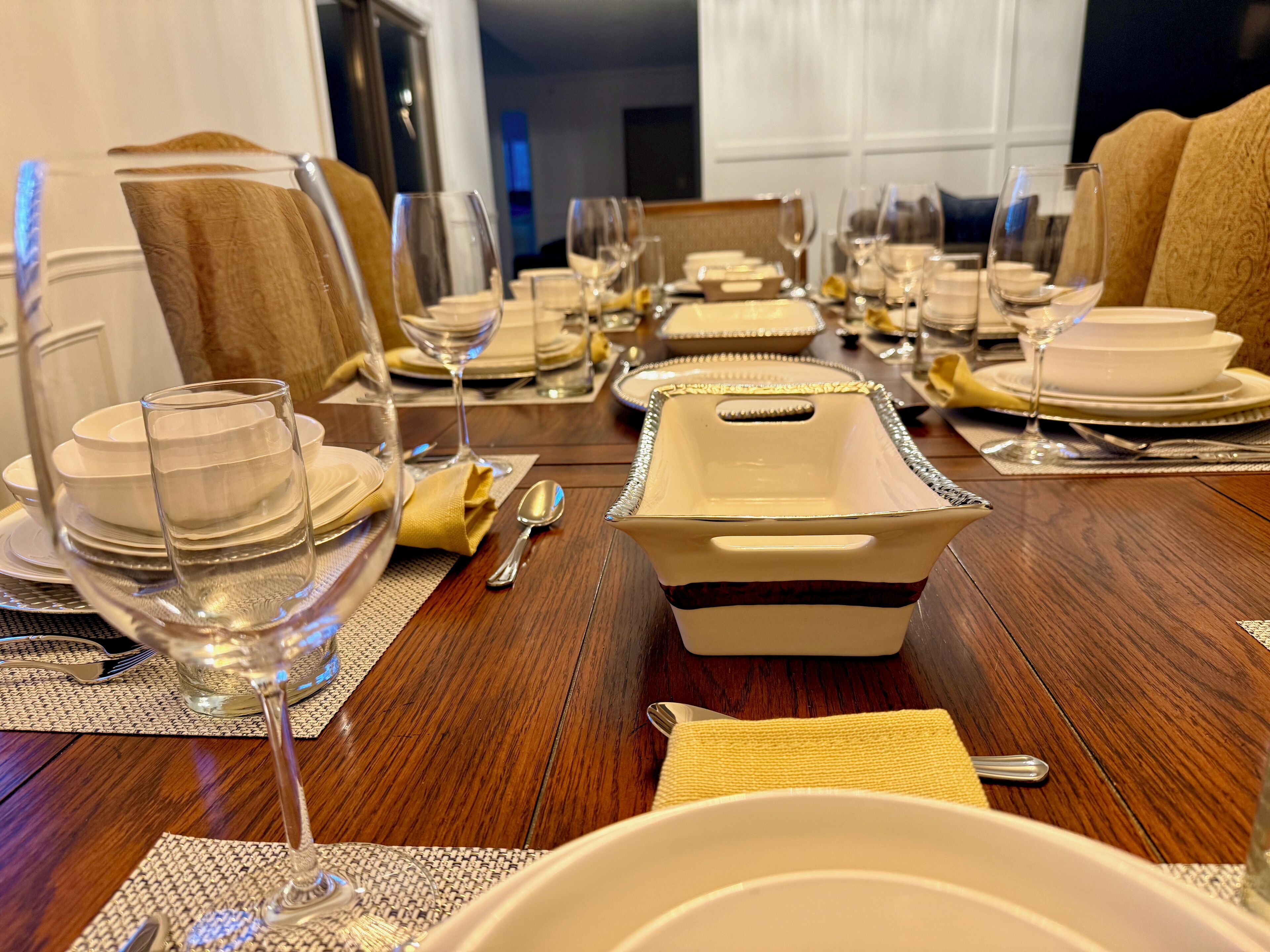 Een eettafel gedekt voor een maaltijd, met meerdere borden, glazen en bestek.
