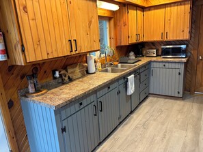 Una cocina con armarios de madera, encimeras de granito, microondas y cafetera.