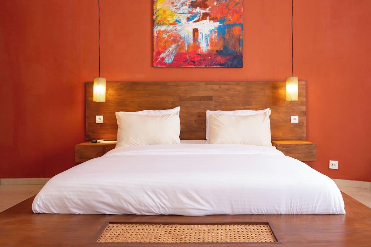 A large bed with white linens, a wooden headboard, and two bedside lamps.