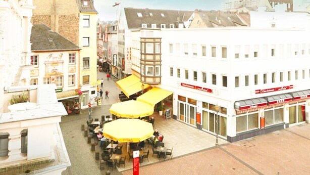 A square with outdoor seating, a statue, and a building with a sign. - Charming vacation apartment in the heart of Koblenz's old town (Koblenz)