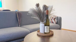 A living room with a grey sofa, a round wooden coffee table, and a bottle of wine on a woven coaster. - Charming vacation apartment in the heart of Koblenz's old town (Koblenz)