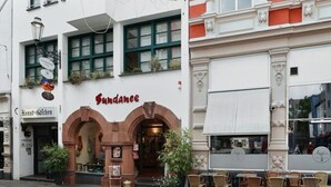 A building with a Sundane restaurant at the ground level, featuring a white facade with green window frames and a red brick section with ornate white detailing. - Charming vacation apartment in the heart of Koblenz's old town (Koblenz)