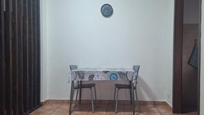 A small dining area with a table and two chairs, a wall clock, and a door leading to another room. - S.I.M residence (MANIAGO)