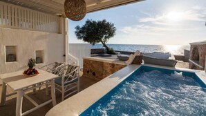 Zona de piscina con vista al mar, una mesa con frutas y una lámpara colgante.