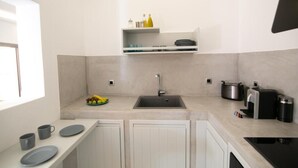 Una cocina moderna con armarios blancos, un lavamanos y una encimera con un frutero.