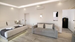 Una habitación de hotel moderna con una cama, un sofá, una mesita y una puerta que da a otra habitación.