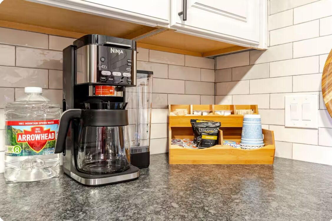 A kitchen with a coffee maker, a water bottle, and a coffee pod holder.