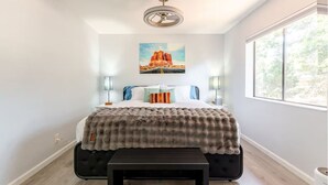 A bedroom with a bed, a bench, a ceiling fan, a painting, and a window. - Charming Red Rock Poolside Condo with WiFi, AC in superb Sedona (Sedona)
