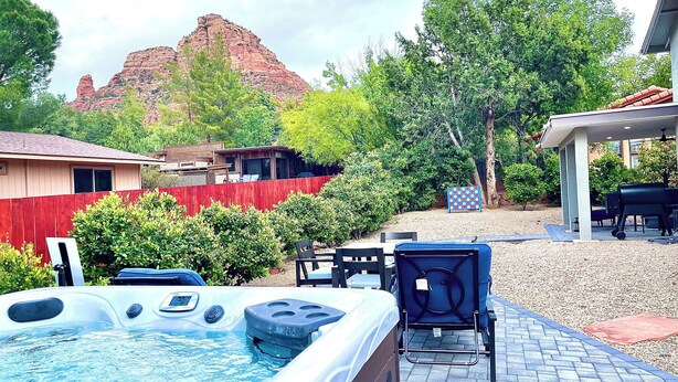 Een achtertuin met een jacuzzi, terrasmeubilair en uitzicht op een berg.