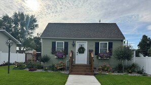 A single-story house with a front porch, a small garden with flowers, and a mailbox. - Spacious 3BR Home - Fast Wifi - Parking - BBQ - Patio - Garden (Williston)